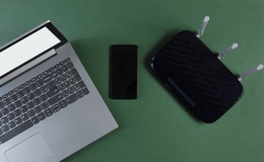 Wi-fi yönlendirici, akıllı telefon, yeşil arka planda dizüstü bilgisayar. Modern aletler. Üst görünüm