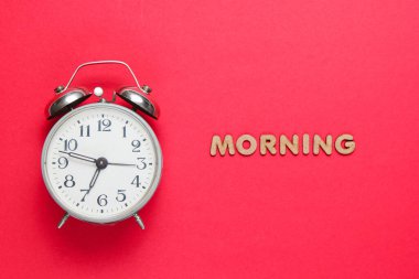 Kırmızı arkaplanda geri alarm saati ile metin sabahı harfleri.