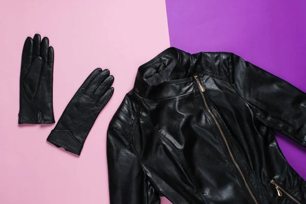 Fashionable women\'s clothing and accessories. Leather jacket, gloves on purple pink background