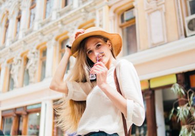 Şehir mimarisinin arka planında şapkalı genç sarışın bir turist portresi.