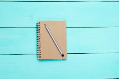 Mavi ahşap masa üzerinde kurşun kalem olan Kraft kağıt not defteri. Üst görünüm