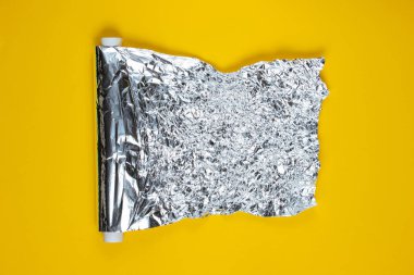 Sarı arka planda buruşmuş bir folyo rulosu. Üst görünüm