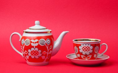 Retro ceramic cup and teapot on red background. Top view