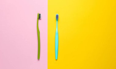 Two new toothbrushes on yellow pink pastel background. Minimalism hygiene concept