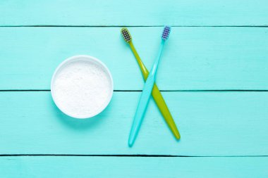 Two toothbrushes, tooth powder on blue wooden background. Minimalism oral hygiene concept. Top view