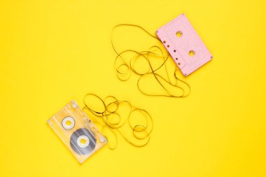 Music lover minimalism concept. Retro style 80s. Two audio cassettes with film on yellow paper background.