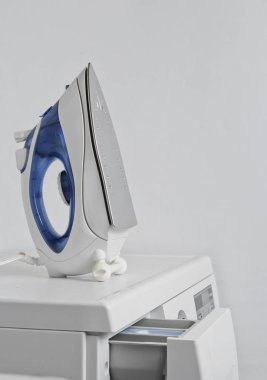 Demir çamaşır makinesinin üzerinde duruyor. Beyaz arkaplanı kapat.