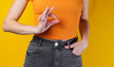 Kadın sarı arka planda bir jest gösteriyor. Ekin fotoğrafı, stüdyo fotoğrafı.