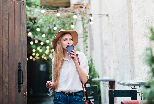 평상복 차림의 매력적 여자가 커피를 마시며 도시의 거리를 다닌다 — 스톡 사진