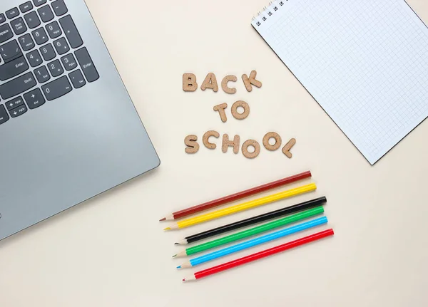 回到学校的简约概念 笔记本电脑 彩色铅笔 米色背景的笔记本 带着木制字母飞返学校 — 图库照片