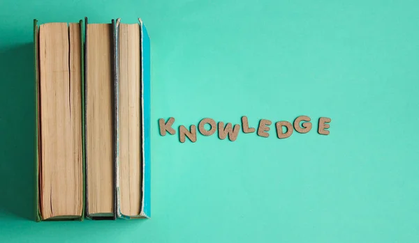 木製の文字の単語の知識と青の背景に古い本のスタック トップビュー ミニマリズム — ストック写真