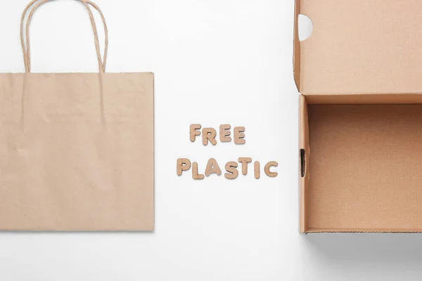 Ecological concept. Empty cardboard box, paper bag on a white background with the word free plastic. Top view