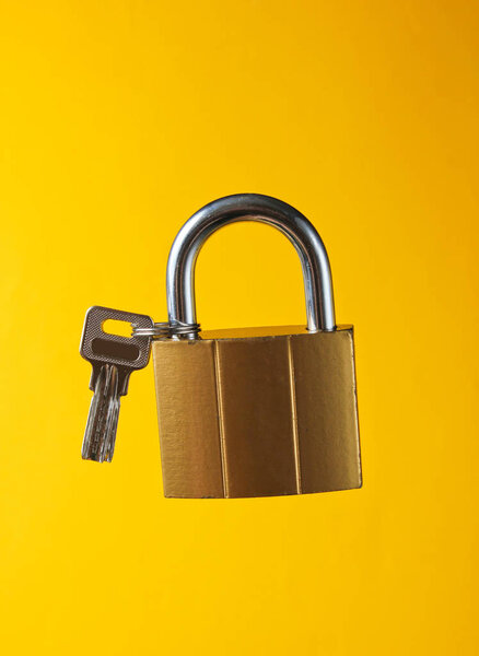 Metal lock with key on yellow background