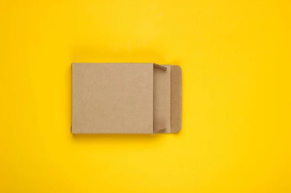 Sarı Kağıt Zemin Üzerinde Boş Karton Kutu — Stok fotoğraf