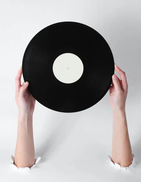白い背景の引き裂かれた穴を通してビニールレコードを保持する女性の手 創造的な芸術レトロなスタイル — ストック写真