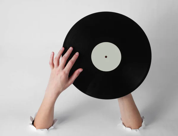 女性の手は 白い背景の引き裂かれた穴を通してレコードを回転させます 創造的な芸術レトロなスタイル — ストック写真