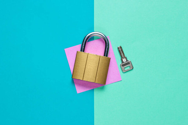 Замок с ключом на цветном бумажном фоне. Вид сверху
