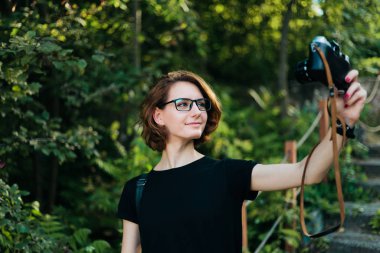 Genç çekici hippi kız dışarıda retro kamerayla selfie çekiyor.