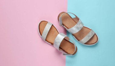 Pastel mavi-pembe arka planda deri kadın sandaletleri. Yaz ayakkabıları, Top view