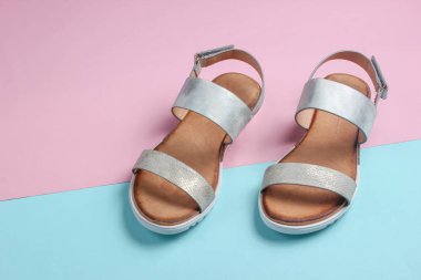 Pastel mavi-pembe arka planda deri kadın sandaletleri. Yaz ayakkabıları