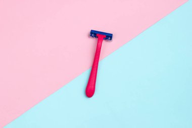 Minimalist güzellik konsepti. Mavi pastel arka planda kırmızı plastik jilet. Üst görünüm