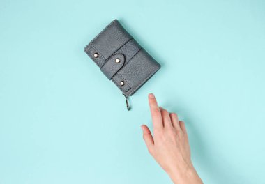 Kadının eli mavi arka planda deri bir cüzdan alır. Üst görünüm