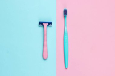 Minimalist kişisel bakım, güzellik konsepti. Plastik jilet, pastel mavi-pembe arka planda diş fırçası. Üst görünüm