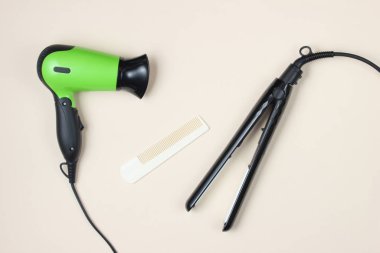 Minimalist güzellik ve moda hala hayat. Bej arka planda saç kurutma makinesi, tarak ve saç düzleştiricisi. Üst manzara, düz uzanma