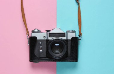 Pembe mavi pastel arka planda kayışı olan deri kapaklı klasik retro film kamerası. Üst görünüm