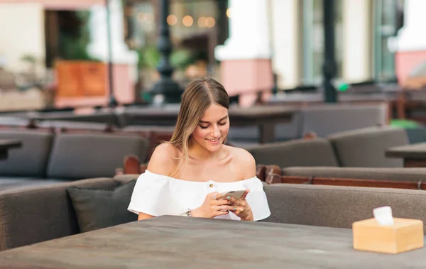 Happy Blonde Woman Holding Smartphone Her Hands While Sitting Table — Stock Photo, Image