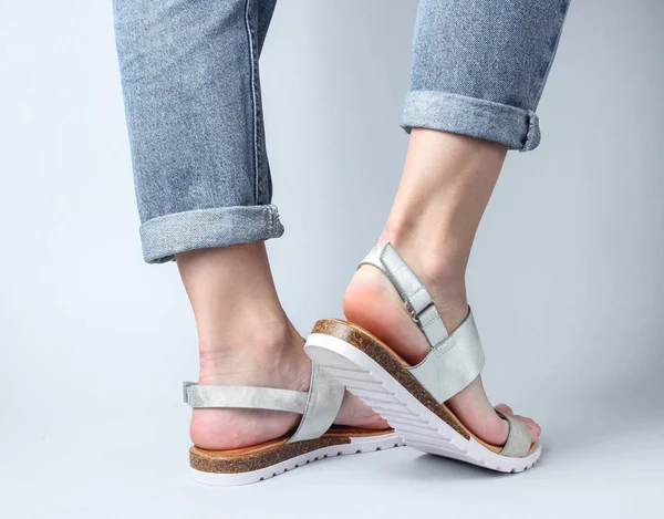 Vrouwelijke Benen Blauwe Jeans Hippe Leren Sandalen Een Witte Achtergrond — Stockfoto