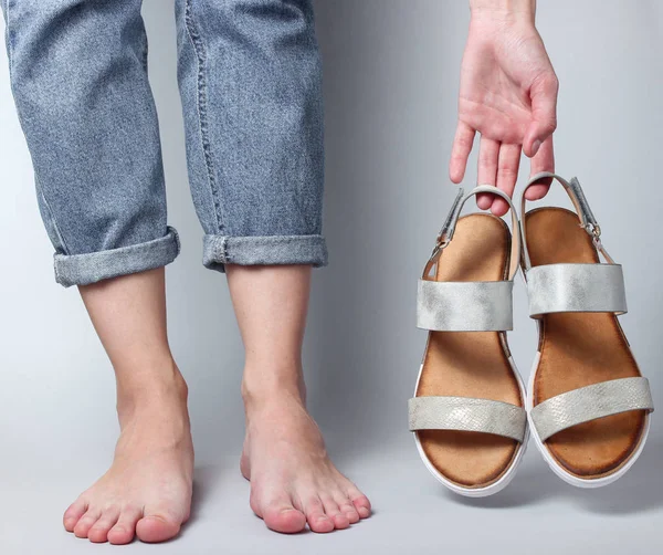 Weibliche Nackte Füße Jeans Und Sandalen Den Händen Auf Weißem — Stockfoto