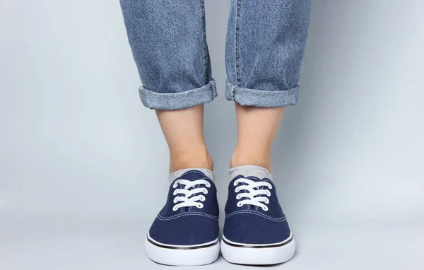 Modestudio Opname Vrouwelijke Benen Jeans Sneakers Een Grijze Achtergrond — Stockfoto