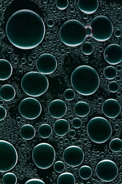 Yuvarlak bir karanlık cam üzerinde parlama ile su damlaları