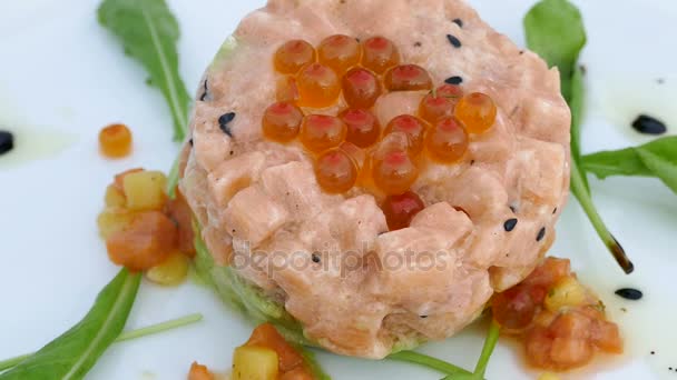 美味的鲑鱼鞑靼与红鱼子酱和 Ruccola 在白色的盘子 — 图库视频影像