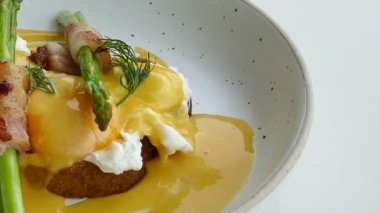 lezzetli Yumurta Benedict pastırma ve beyaz tabak içinde kuşkonmaz ile 