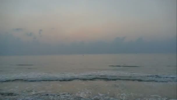 Západ slunce z mořských vln, písečná pláž a dramatické nebe, časová prodleva