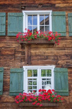 Çiçek kutularıyla çerçevelenmiş güzel pencereler. Pencerelerde renkli süslemeler var. Kırsal pencere çerçevesi 