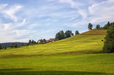 Almanya 'nın kalbinde yeşil yuvarlanan tepeler ve çiftlik evleri olan renkli bir manzara.