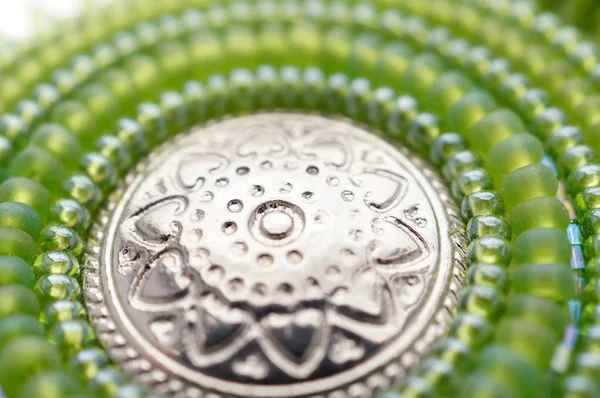 Seed bead embroidered green mandala with metal button.