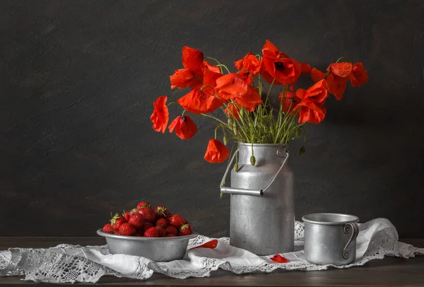 Natureza morta em um estilo rústico: chapa de alumínio e lata, buquê de papoilas vermelhas e morango em uma mesa de madeira . — Fotografia de Stock