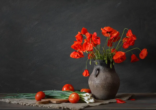 Still life in a rustic style: an old crock, bouquet of red poppies and a vegetables on a wooden table. — Stock Image Still life in a rustic style: an old crock, bouquet of red poppies and a vegetables on a wooden table. Stock Image