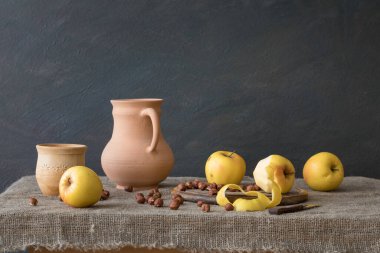 Still life in rustic style. A set of pottery, apples and hazelnuts on the table.  Natural light from the window.
