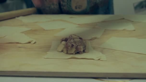Γυναίκα, βάλτε την γέμιση του κιμά κρέατος στα κομμάτια της ζύμης. — Αρχείο Βίντεο