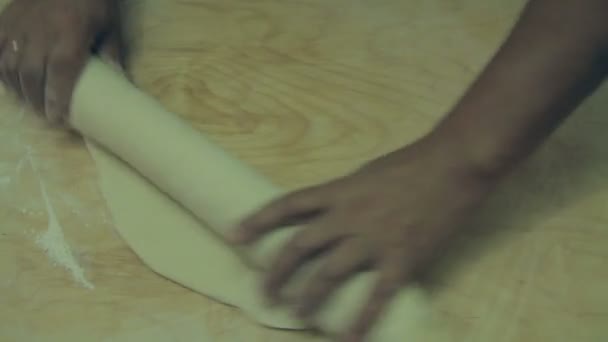 Een vrouw uitrollen het deeg op een vlakke houten ondergrond. — Stockvideo