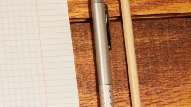 Carnet scolaire dans une cage avec stylo et crayon sur table en bois — Video