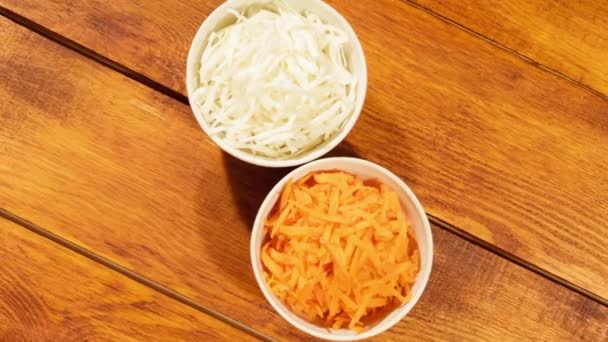 Ψιλοκομμένο καρότο και λάχανο λευκό Κύπελλο σε φόντο ξύλινη κοντινό πλάνο. Υλικά για την σαλάτα λαχανικών — Αρχείο Βίντεο
