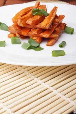 Beyaz bir plaka üzerinde yeşil soğan ile pişmiş havuç.