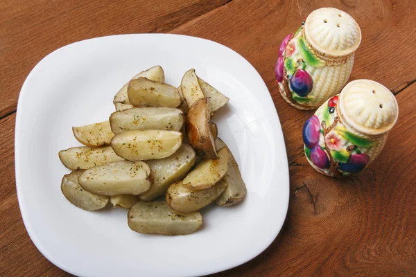 Patate al forno su un piatto bianco. Cibo vegetariano biologico su sfondo di legno — Foto Stock