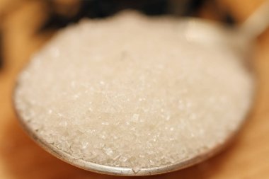 Şeker kum bir gümüş kaşık ve bir ahşap arka plan